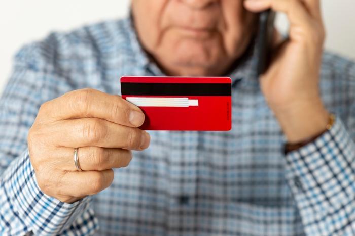 Man holding credit card listening to phone