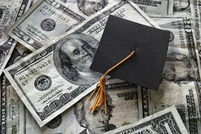 Graduation cap on top of pile of money