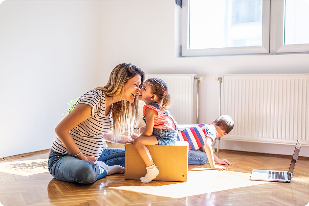A mom plays with her kids in the living room of their new home. 