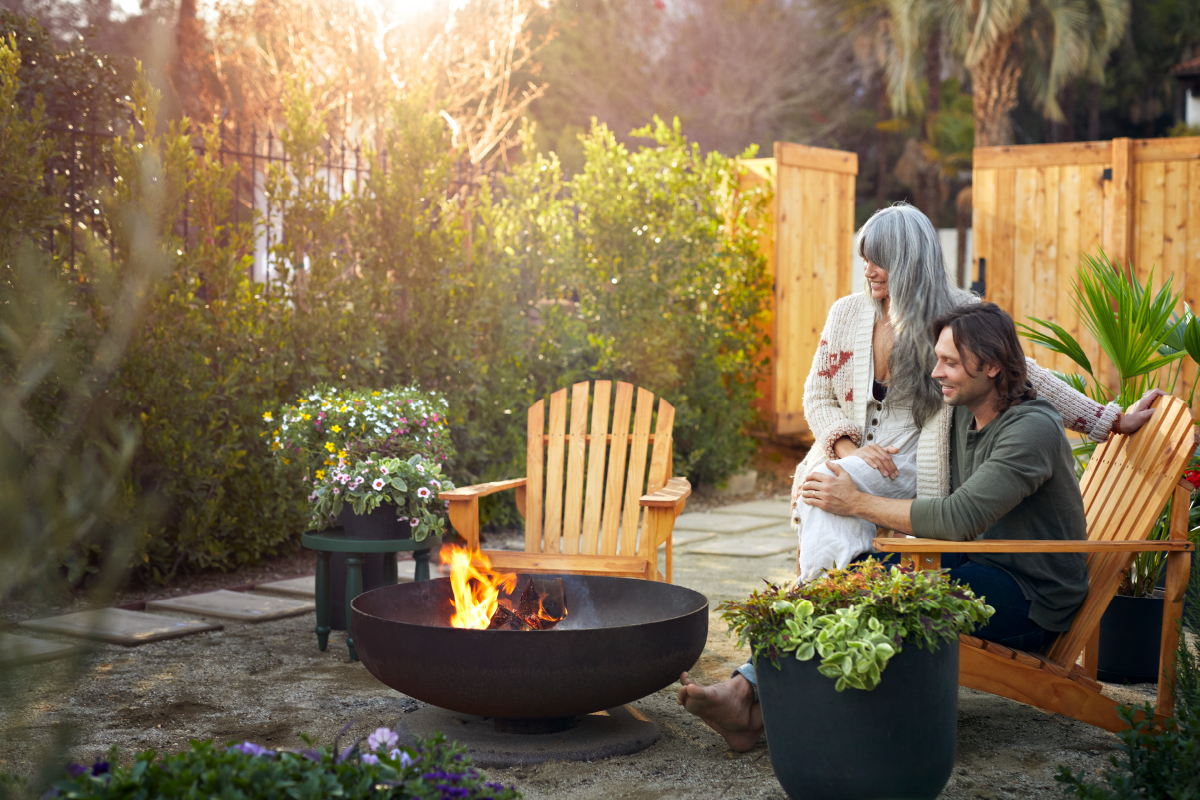 Couple sitting on their patio chairs by a fire pit enjoying their decked out patio