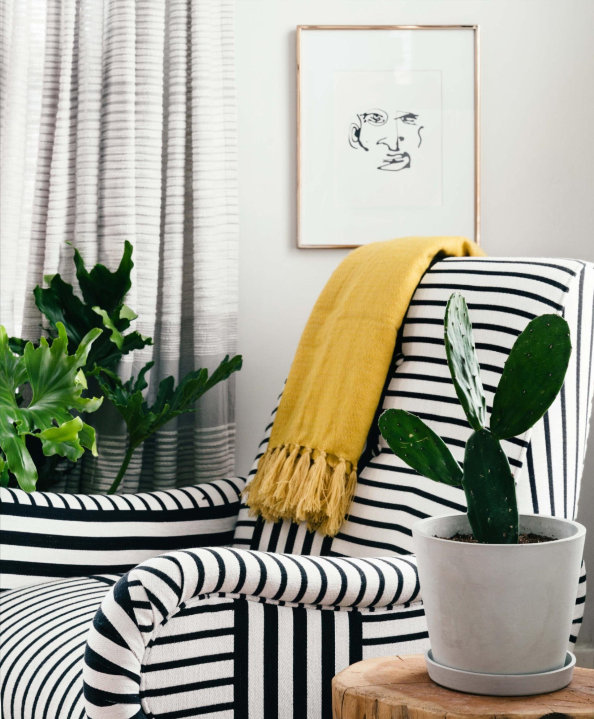 An arm chair with an end table and a potted cactus.