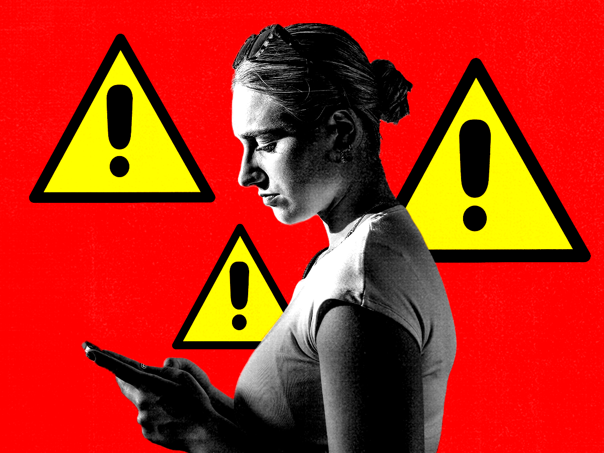 Woman in profile looking down at a phone on red backdrop with yellow caution signs behind her