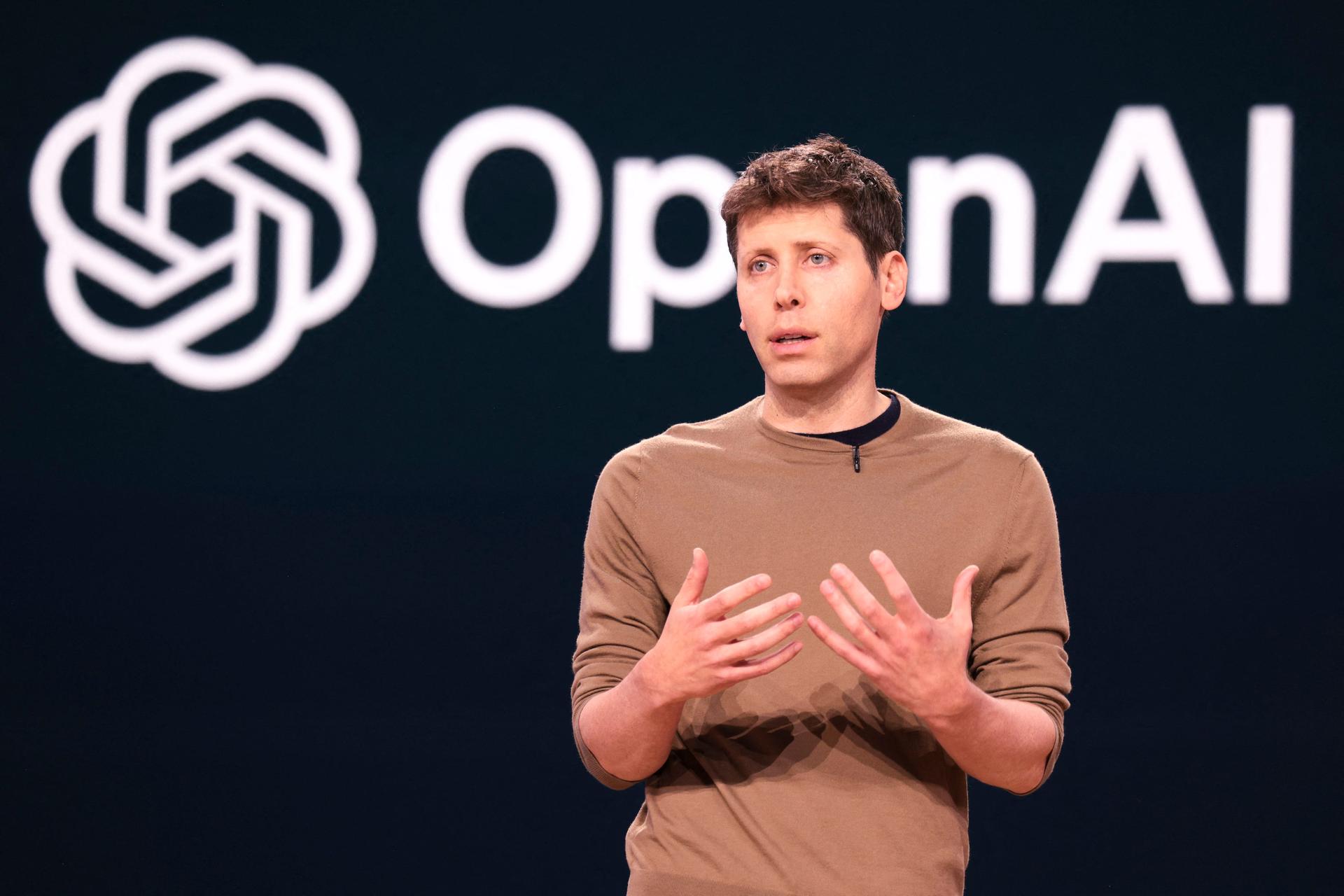 Image of Sam Altman speaking in front of OpenAI logo