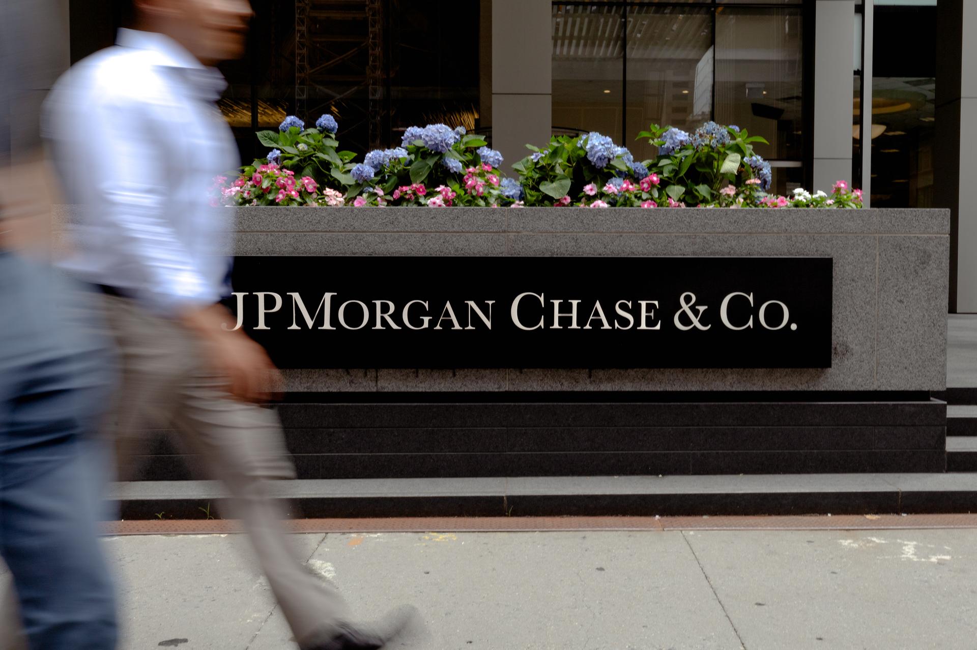 Image of JP morgan sign outside office building with man walking past