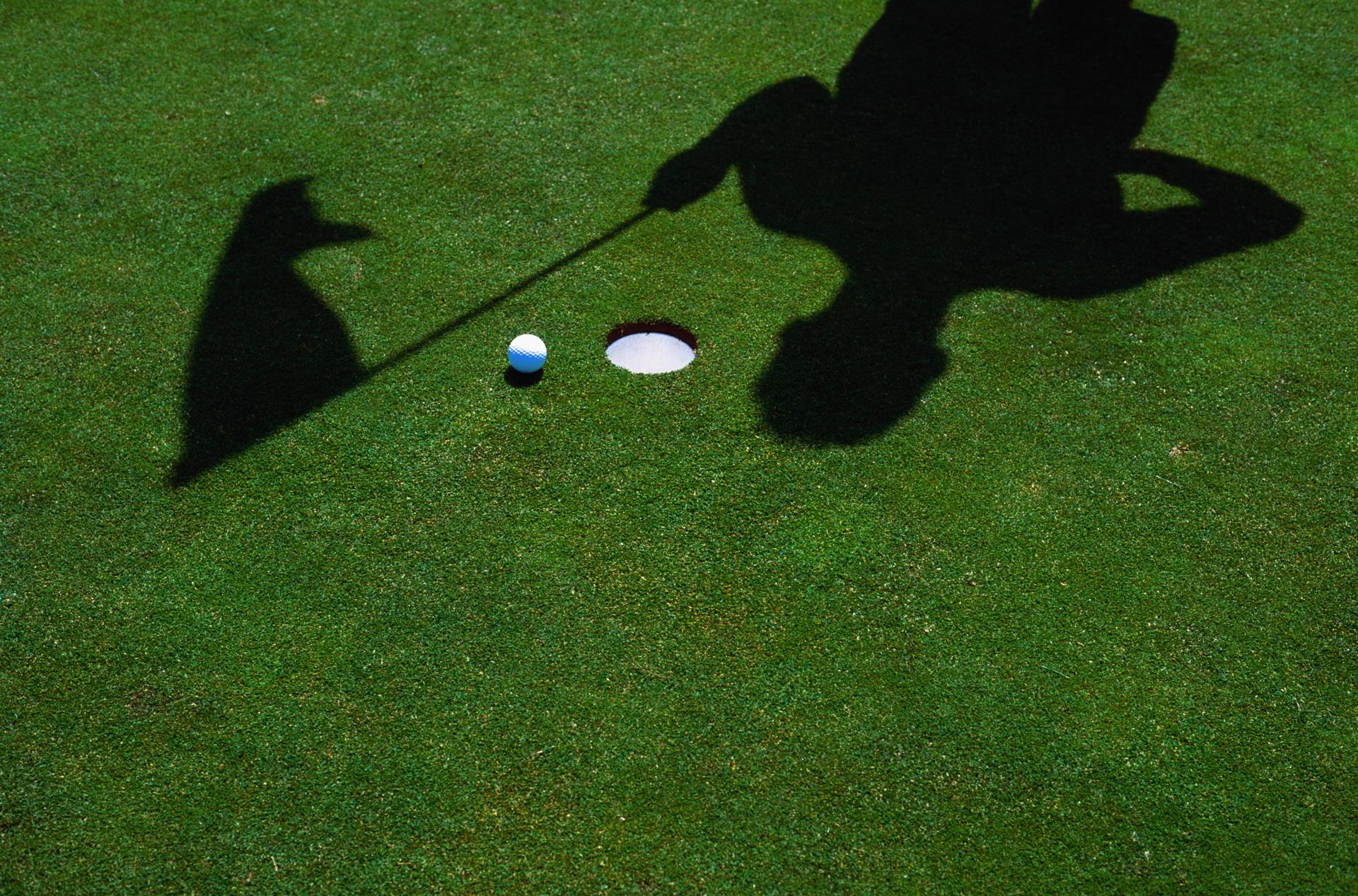 A stock image of a shadow of a golfer on a golf course.