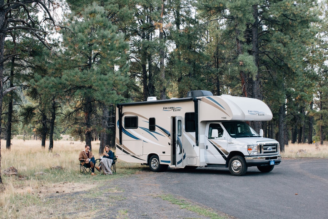Couple sitting in front of RV in the woods
