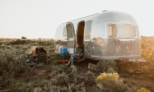 Person sitting outside f airstream in the desert