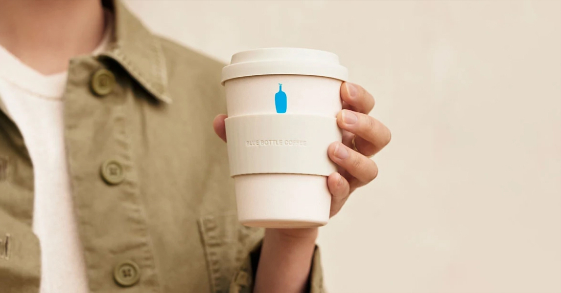 Image of person holding Blue Bottle branded cup