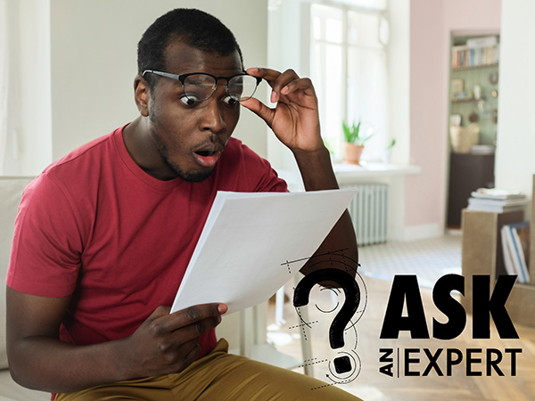 Shocked man lifting glasses looking at paper.