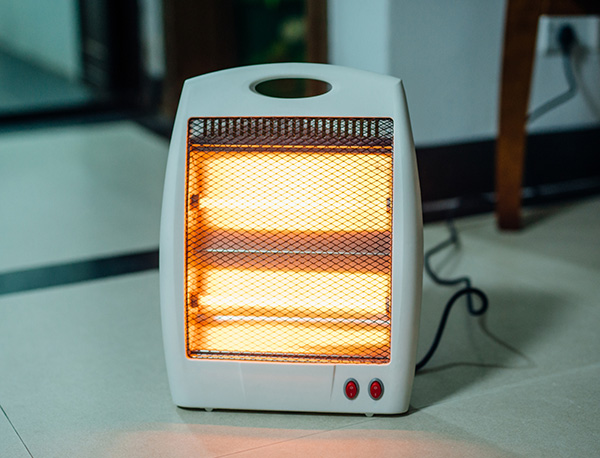 Electric heater glowing on tile floor.