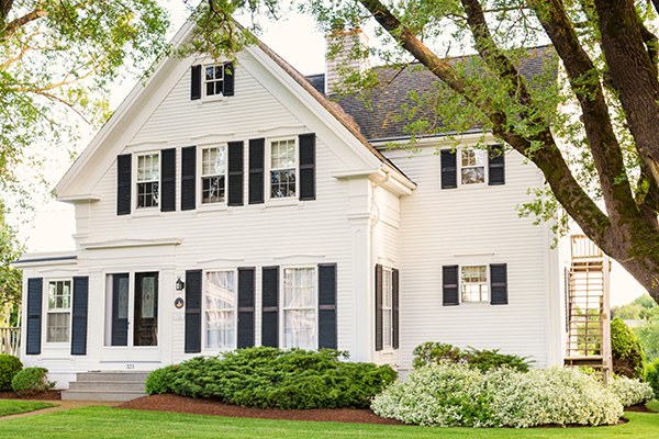 Large white house with black shutters and landscaping