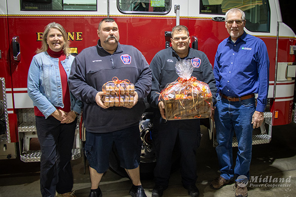 Midland Power employees delivering gift baskets to two local firefighters.