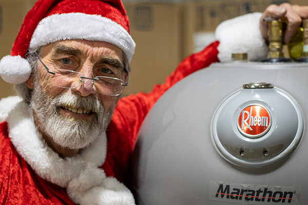 Man dressed as Santa wrapping his arm around Marathon®️ water heater.