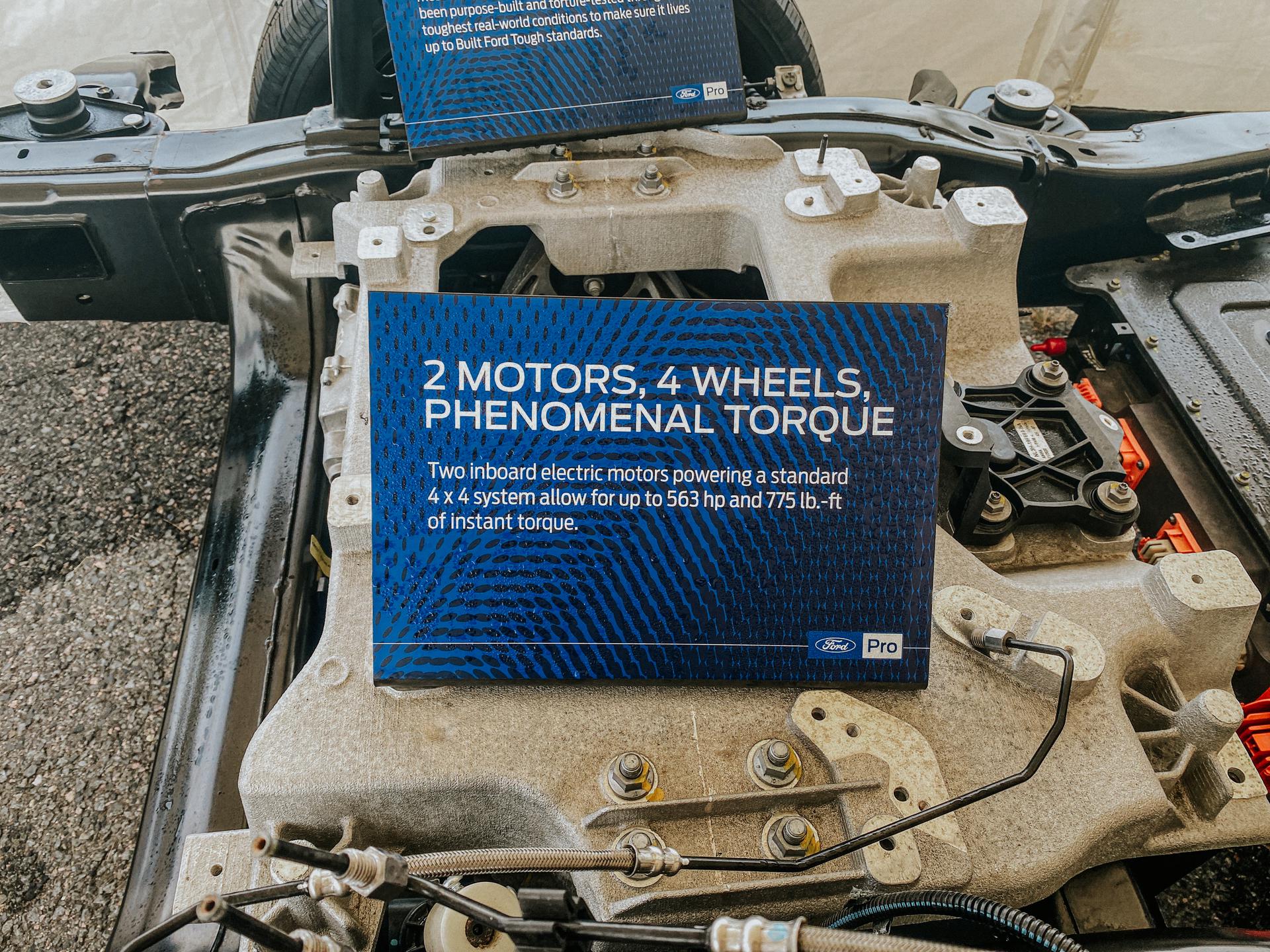 A placard resting on the exposed frame of a 2022 Ford F-150 Lightning that reads ''2 Motors, 4 Wheels, Phenomenal Torque. Two inboard electric motors powering a standard 4 x 4 system allow for up to 563 hp and 775 lb.-ft of instant torque.