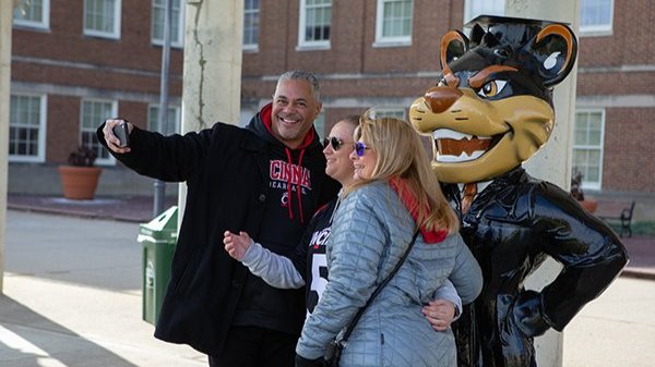 Alumni taking a selfie with a Bearcat statue