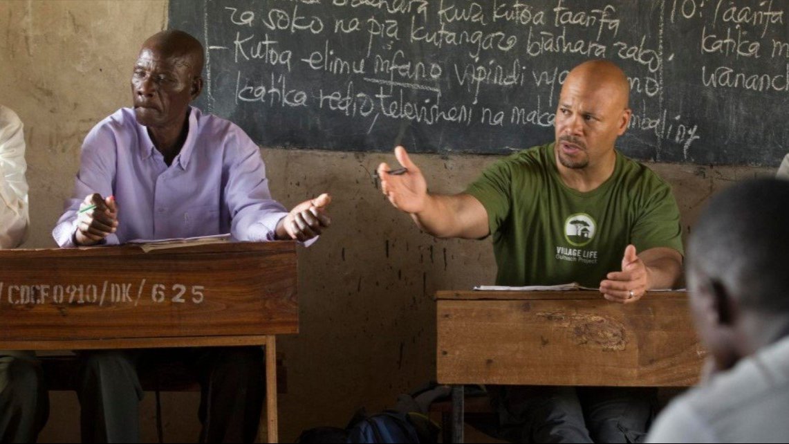 two men talking in front of a group