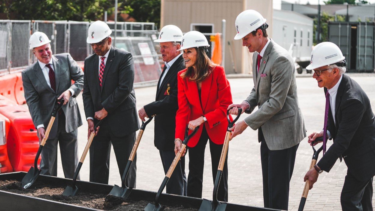 group of people wearing hard hats and holding shovels