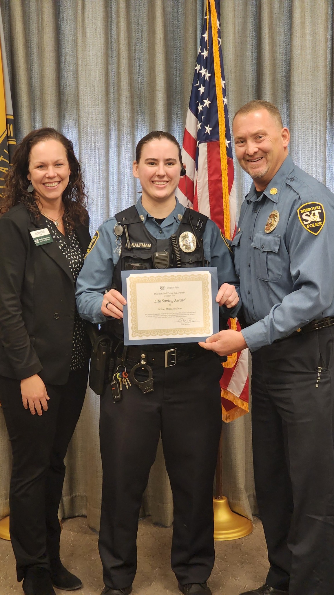 Three people with one being awarded a certificate.