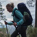 Eine Wanderin im Vordergrund, im Hintergrund Wald und Felsen