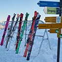 Ski stehen am Skiständer, im Vordergrund Wegweiser
