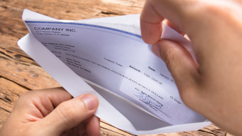 hands opening an envelope with a check inside