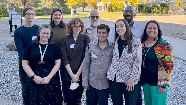 A group of nine people pose together in an outdoor setting.