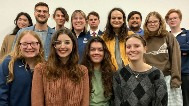 The Whitman College Debate Team stands smiling against a light background.