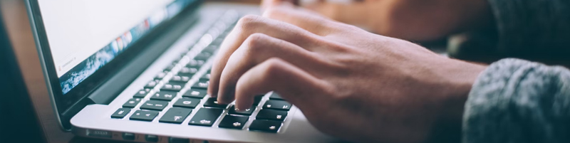 Hands typing on a laptop keyboard.