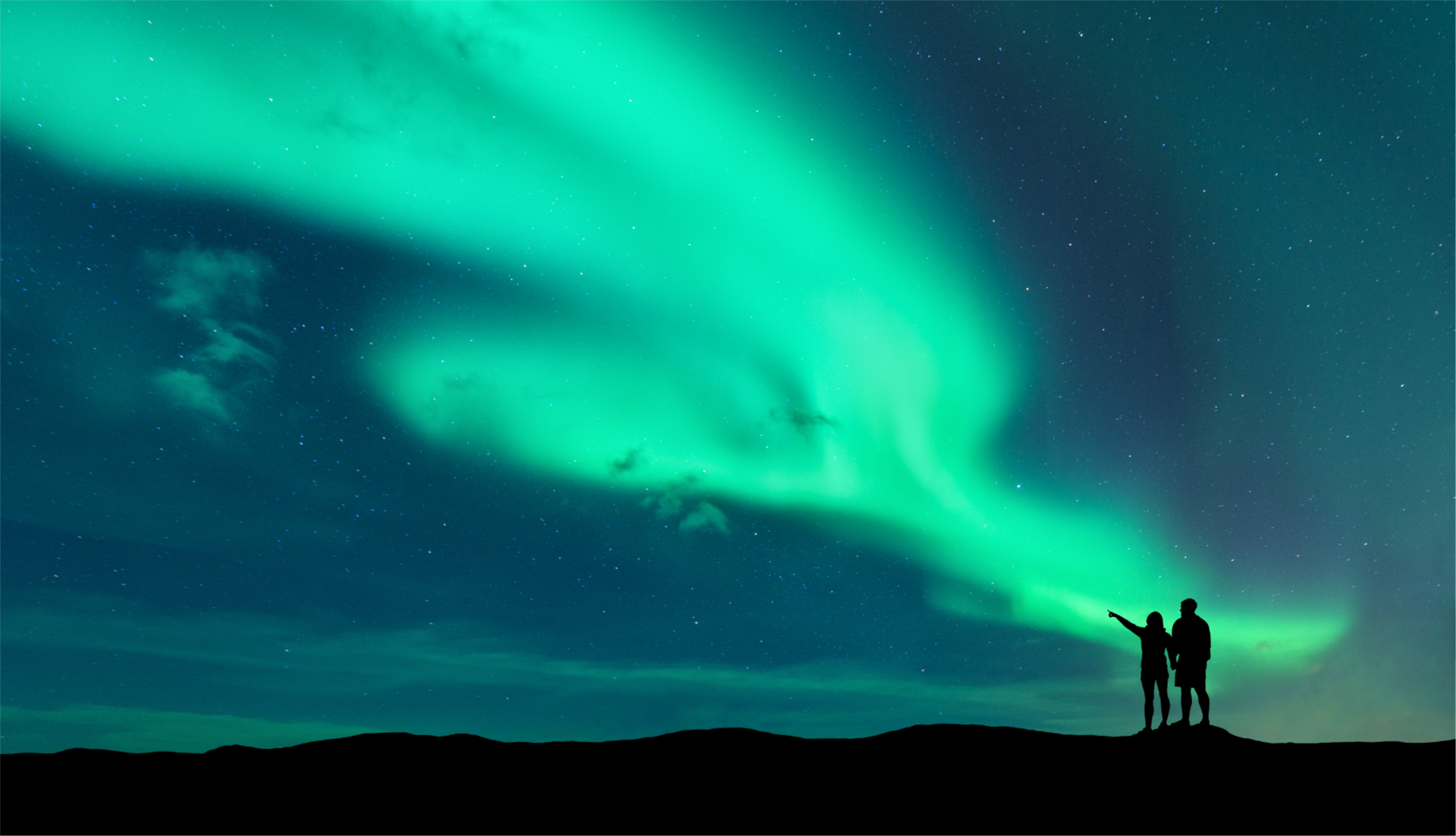 Couple looking at green glow of the northern lights