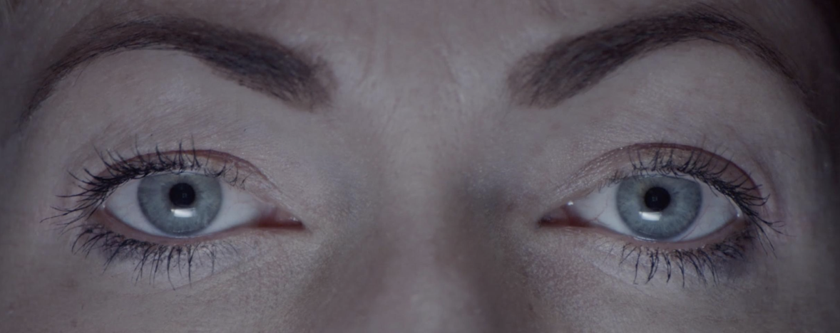 a ligh-skinned women with blue eyes stares into the camera