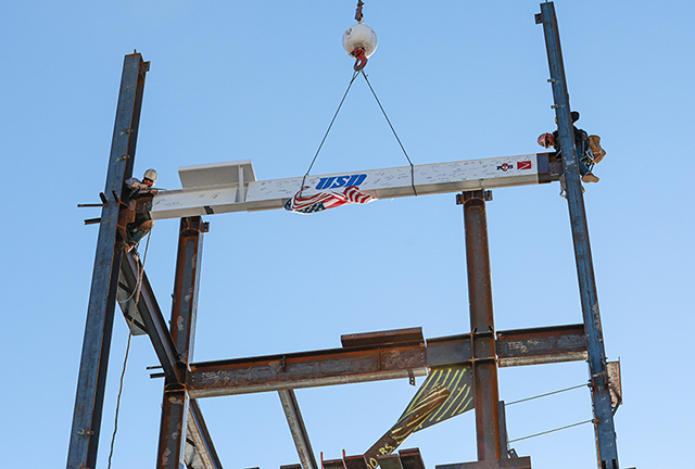 A signed beam is lowered into place on the new Wellness Center