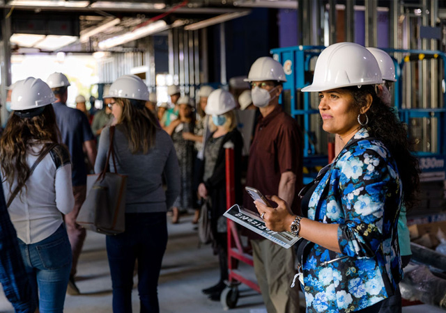 Image of USD faculty member and alumni wearing a hard hats while touring the KCBE construction site