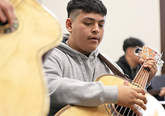 A mariachi student plays bass guitar