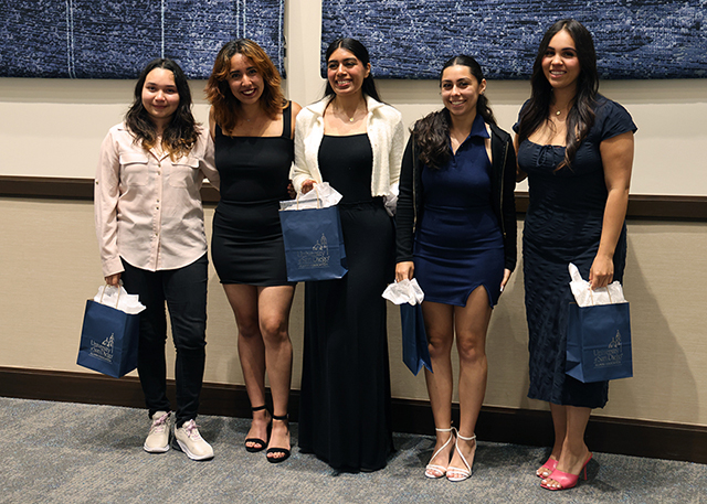 Five graduates smile in the Ministry Center