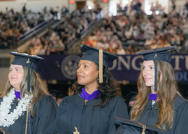 Graduate students take in commencement inside the Jenny Craig Pavilion.