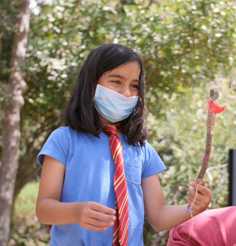 A student in the Forest School program holds a wand.