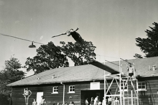 Black and white image of a woman diving backwards into a pool