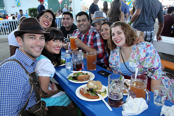 People sat at a table for Oktoberfest, drinking beer and eating