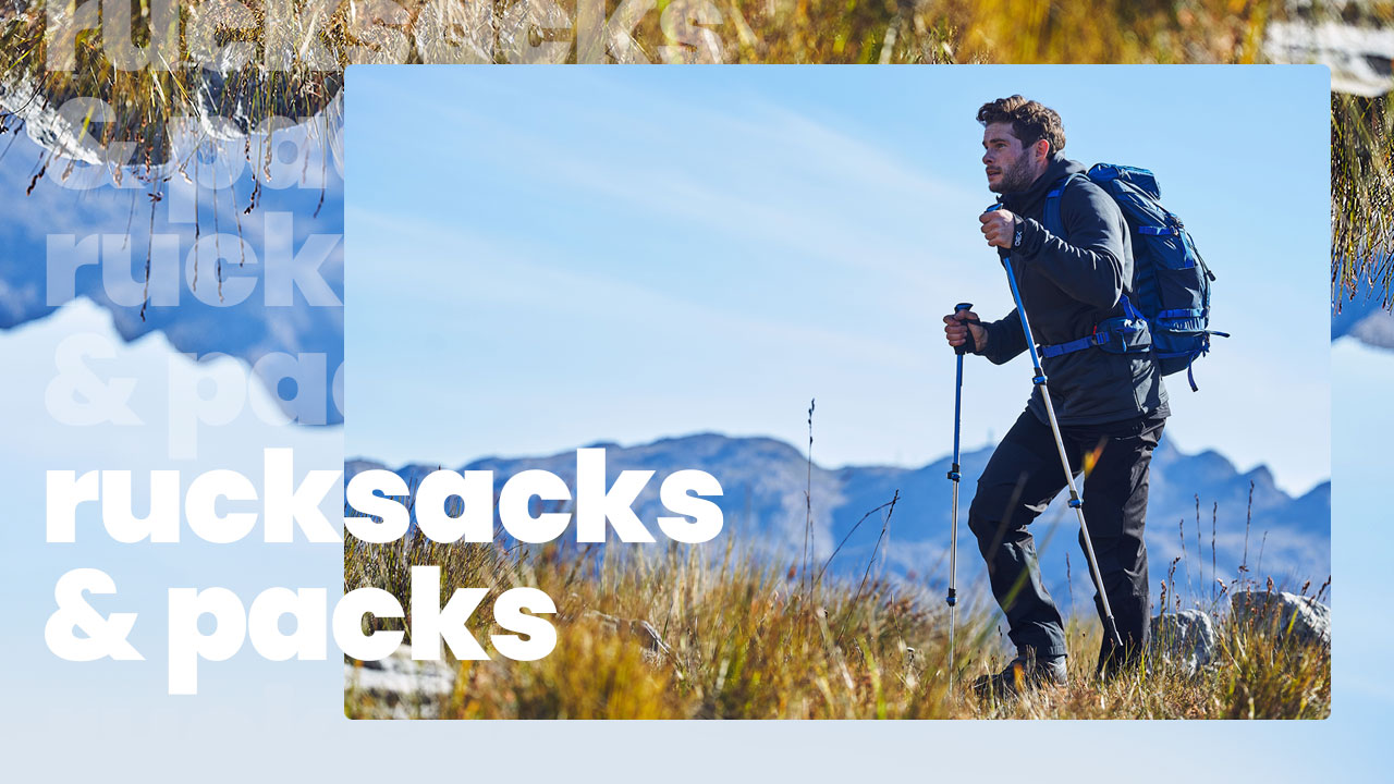 A person walking in the mountains wearing a rucksack and using walking poles.