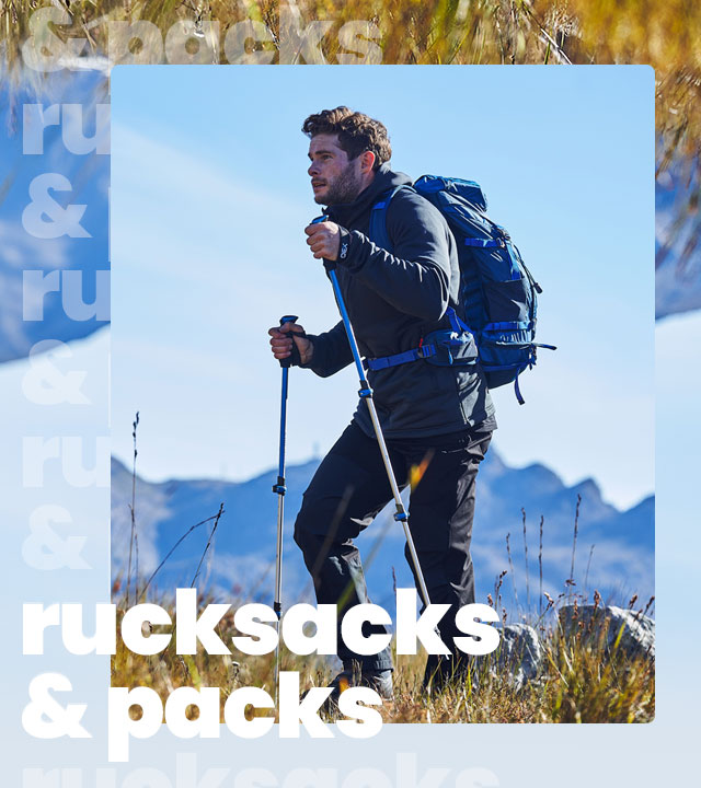 A person walking in the mountains wearing a rucksack and using walking poles.