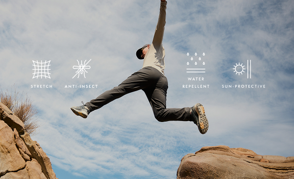 A person jumping a gap between two rocks in the desert