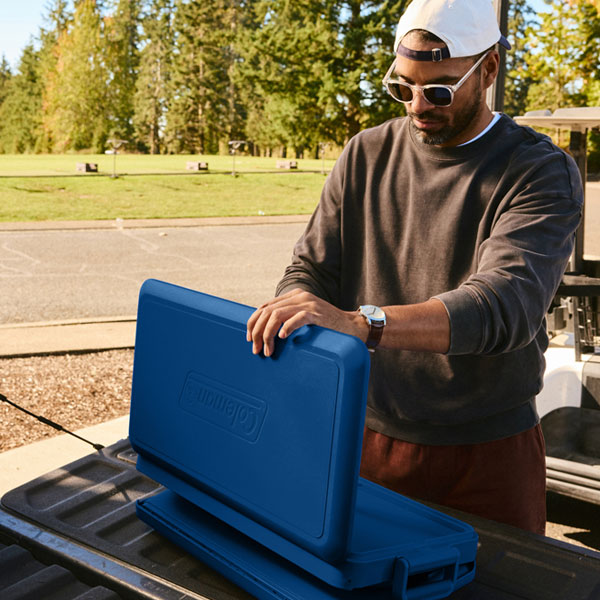 A person setting up their cooler on the back of their truck.