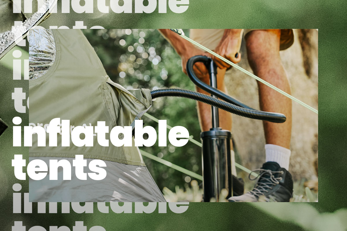 Close-up of a camping scene showing a green inflatable tent being filled with air using a black hand pump. A person’s lower legs and hands are visible while operating the pump, with the hose connected to the tent’s air valve. The setting appears outdoors among trees, with soft, natural light and blurred greenery in the background. 