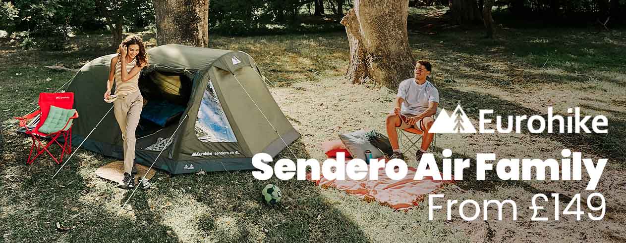 Man and woman sitting outside a tent In a field 