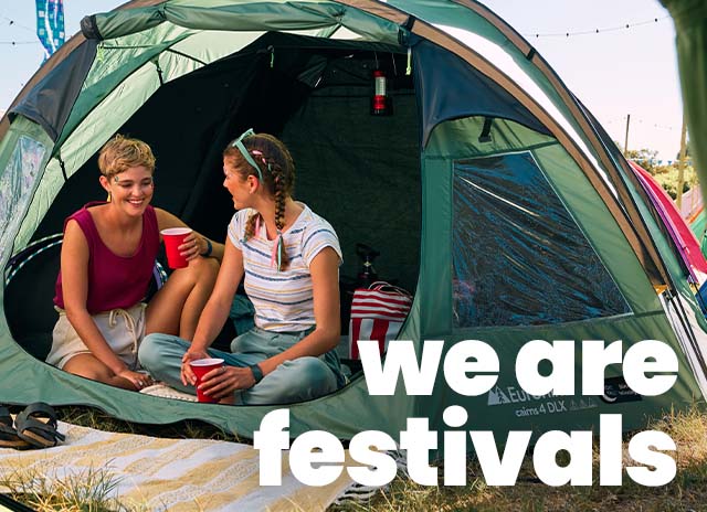 Women sitting inside a green tent at a festival