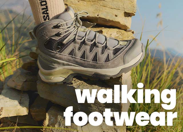 Hiker wearing a walking boot standing on a rock