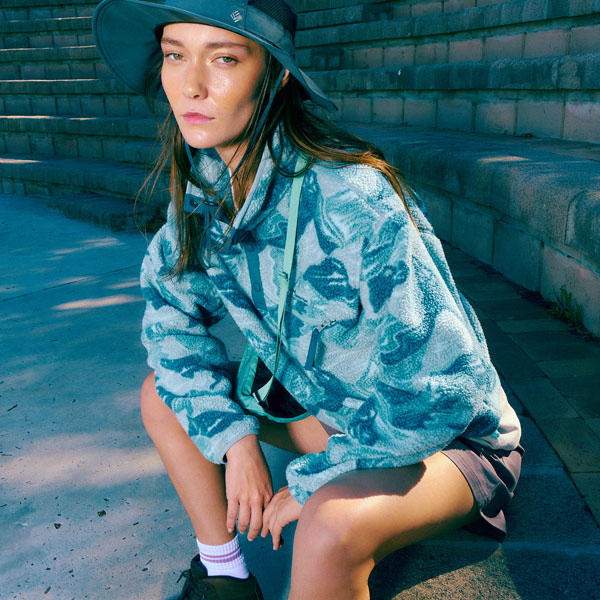 A woman sat down on a stone bench wearing a colourful patterned fleece