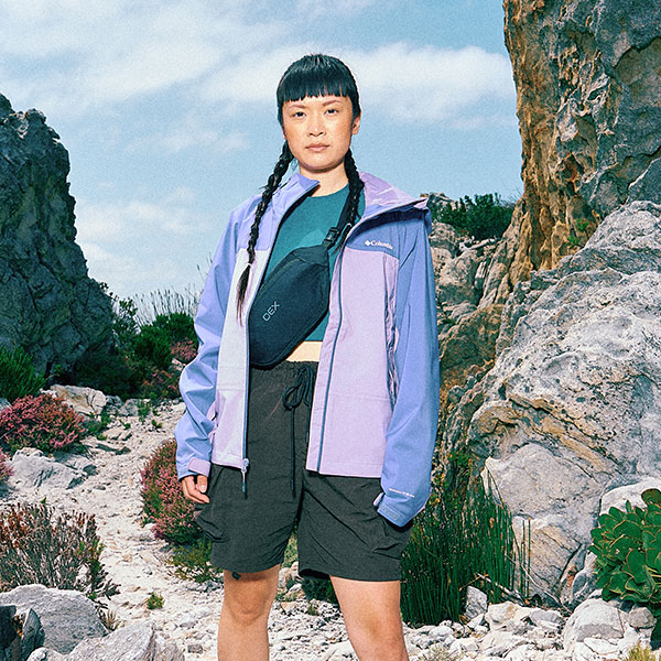 A woman wearing a two-tone waterproof jacket and shorts in the mountains