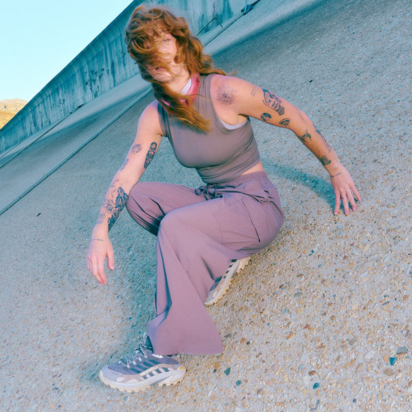 A woman wearing trousers and a vest sat down on some rocks