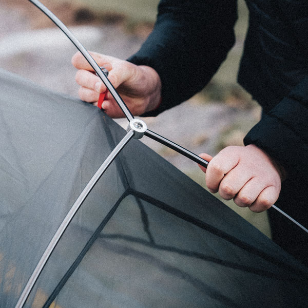A person clipping in tent poles whilst setting up their tent.